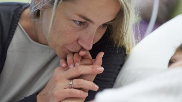 Woman kissing hand of young girl in hospital